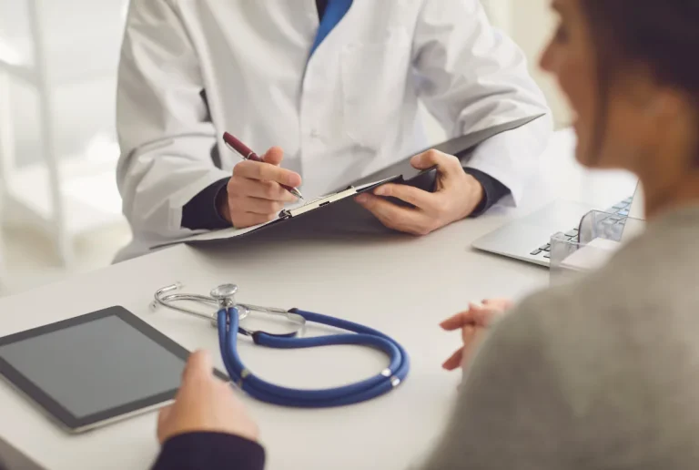 Médico preenchendo documento com estetoscópio sobre a mesa